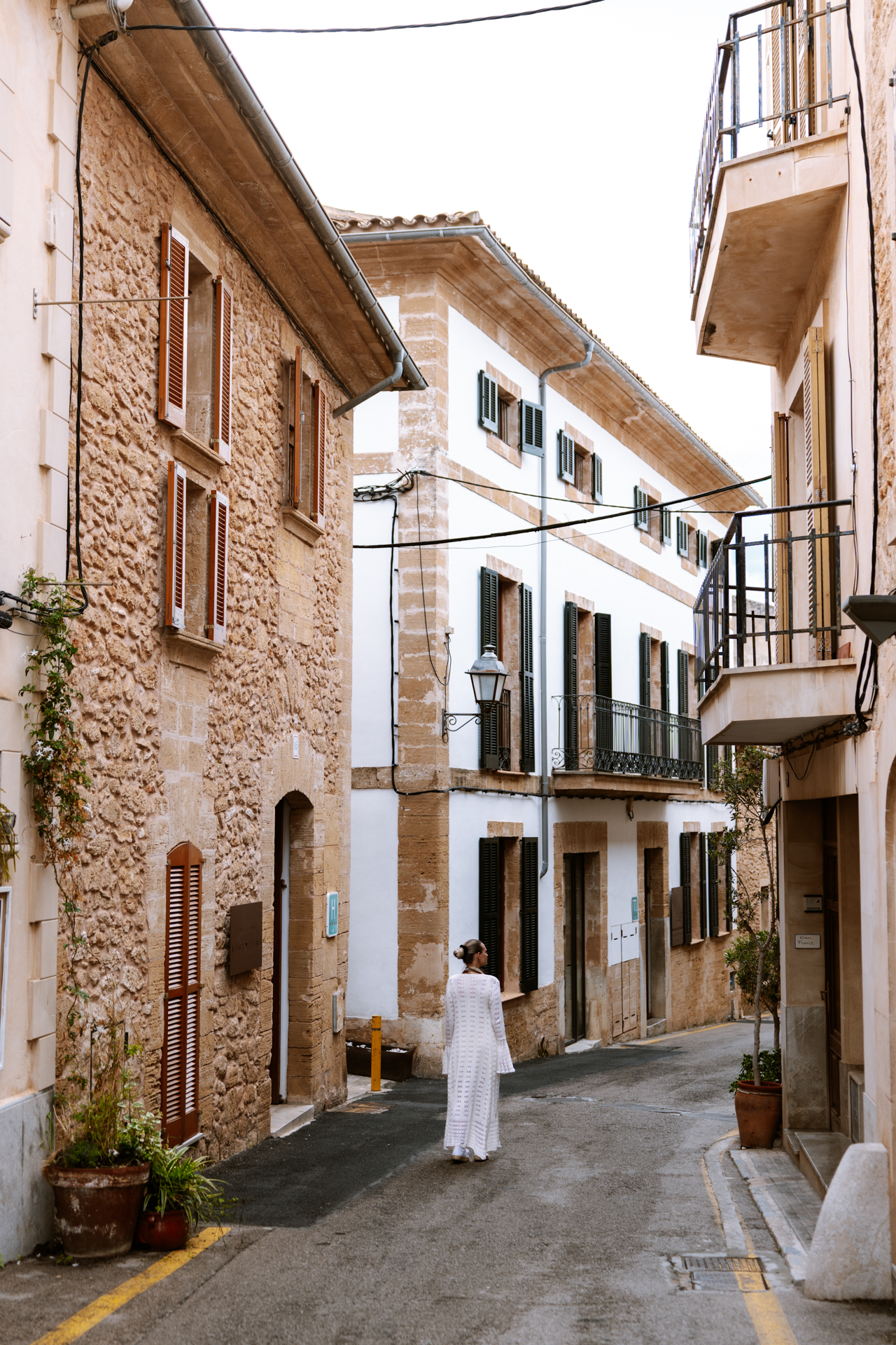 Woman walking through a quiet historic street in Alcúdia Old Town, Mallorca.