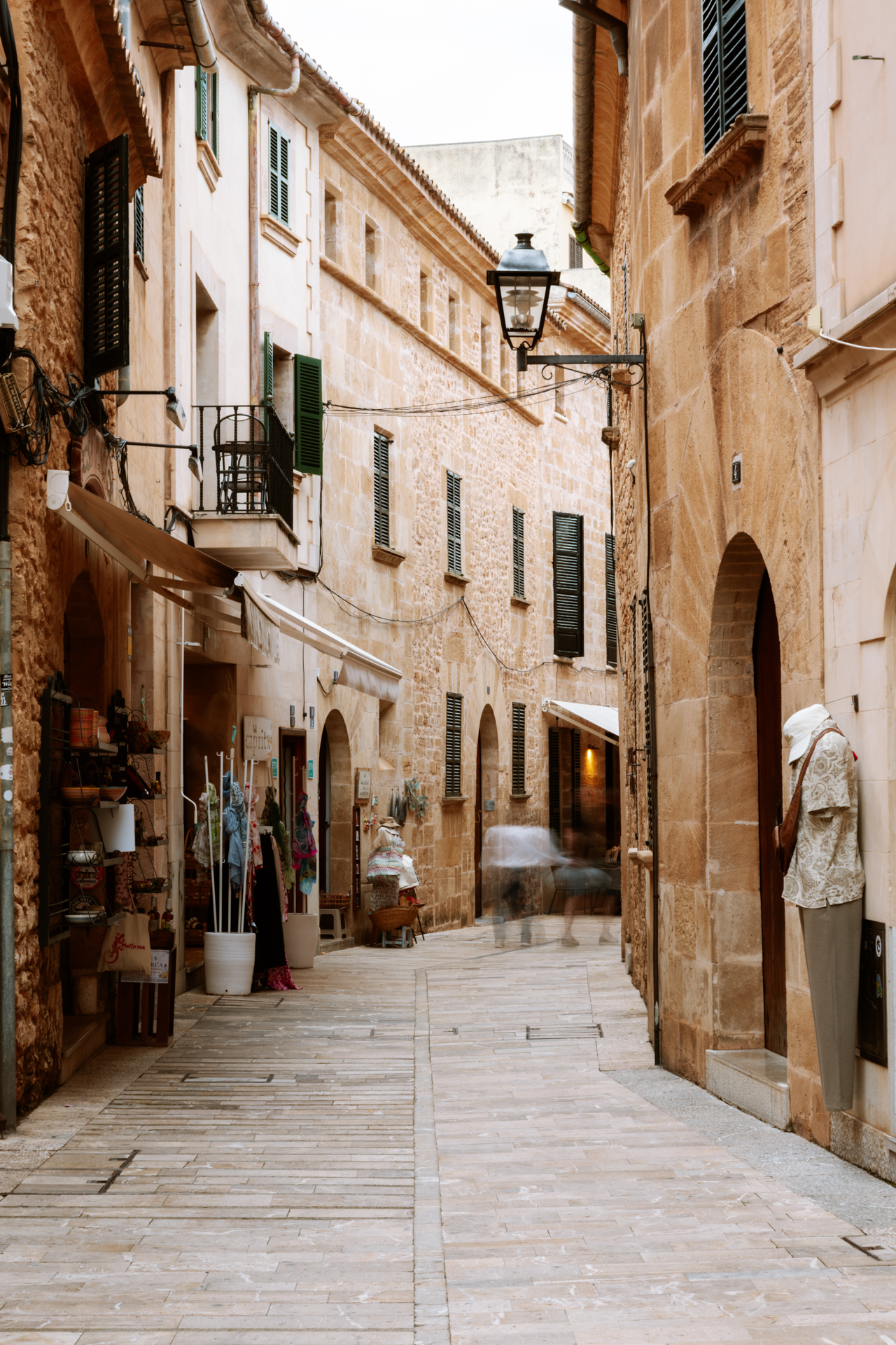 Narrow shopping street with stone buildings in Alcúdia Old Town, Mallorca.