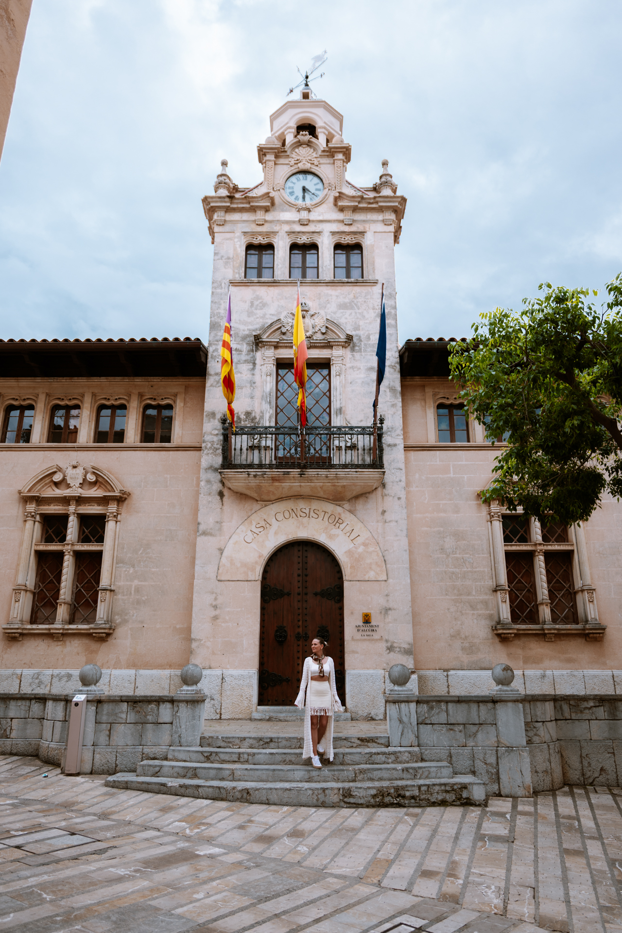 Woman standing in front of Alcúdia Town Hall in Plaça de la Constitució, Mallorca.