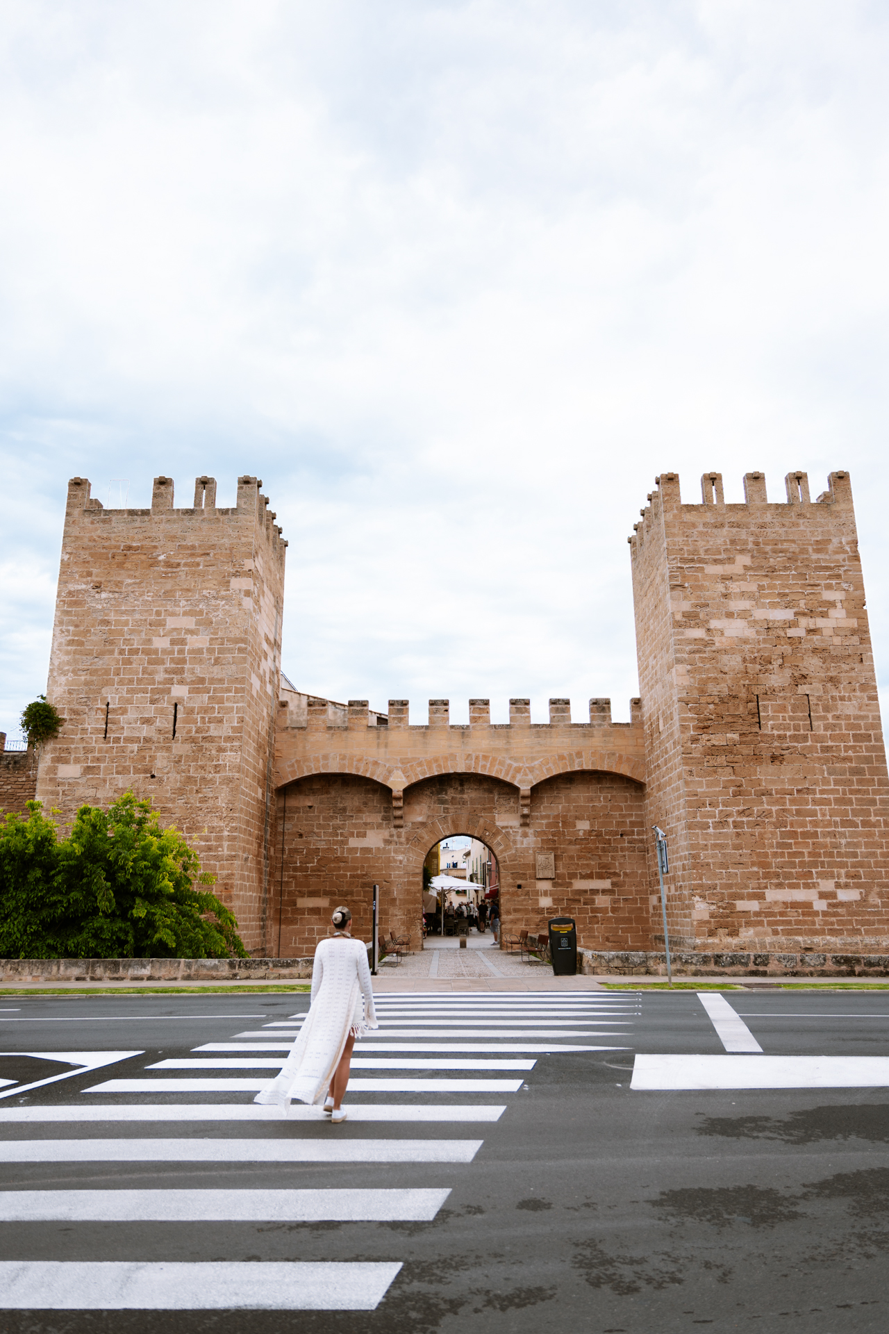 Woman walking toward the medieval Porta de Mallorca gate in Alcúdia Old Town, Mallorca.