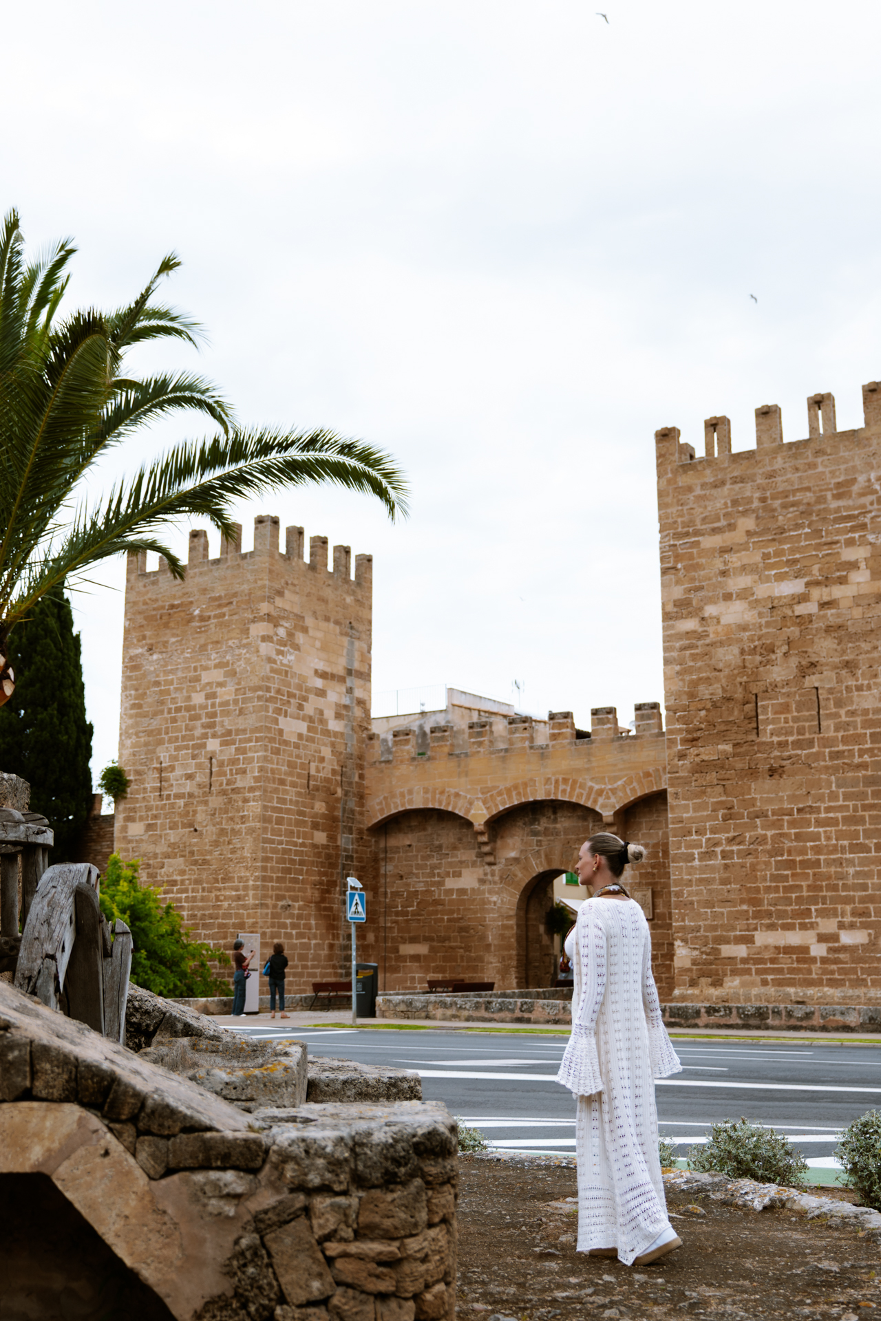 Woman standing near the medieval Porta de Mallorca gate in Alcúdia Old Town.