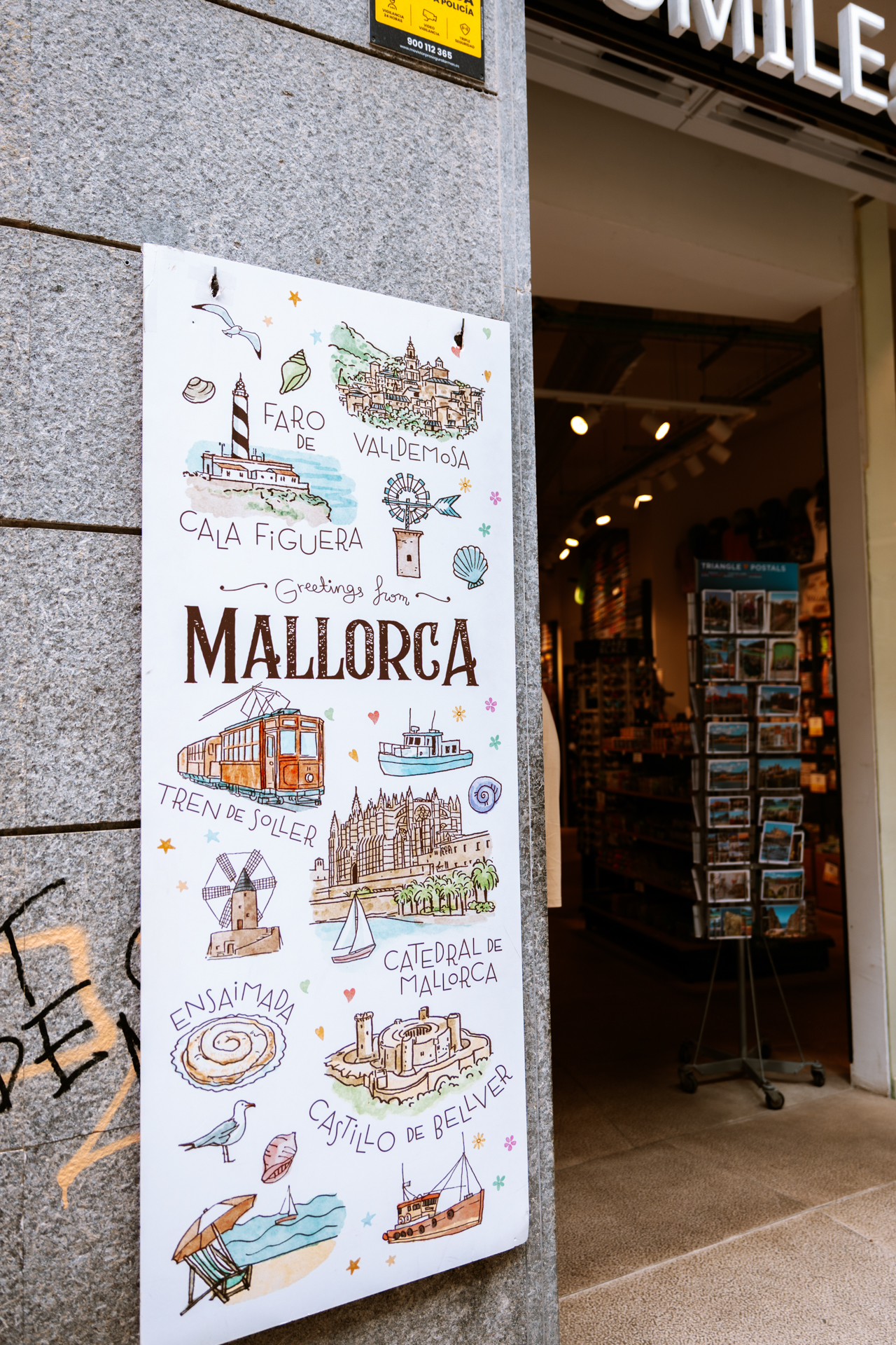 Mallorca postcard sign showing famous island landmarks outside a souvenir shop in Palma.