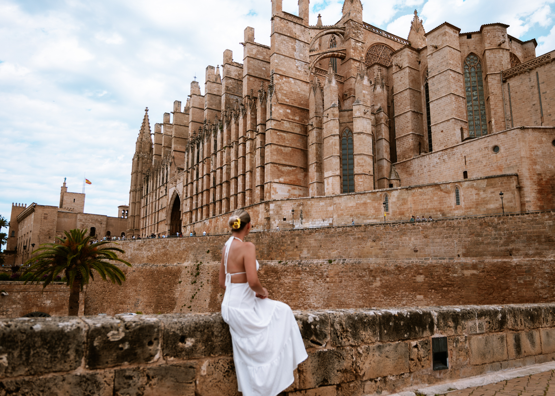 Woman in a white dress overlooking Palma Cathedral in Mallorca, Spain.