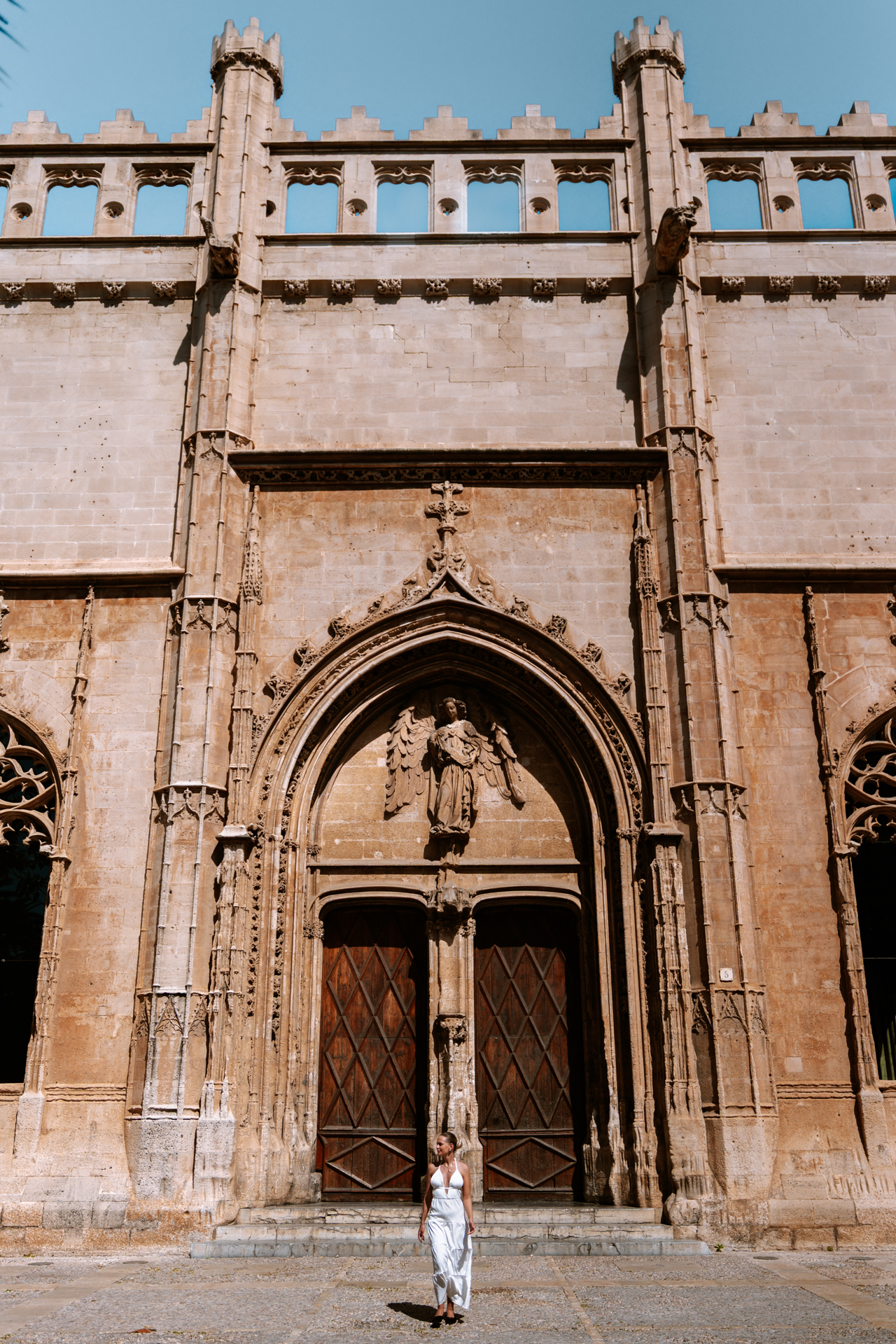 Woman in a white dress standing in front of aSa Llotja in Palma de Mallorca, Spain.