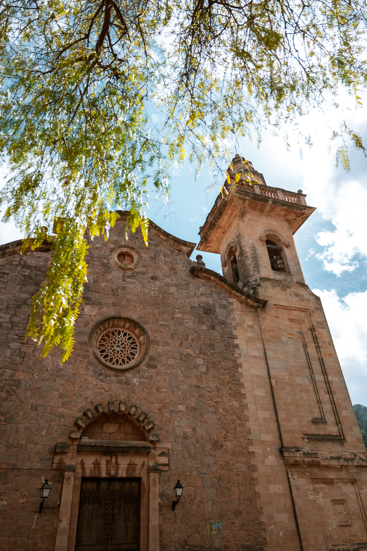Historic church of Valldemossa framed by trees in Mallorca