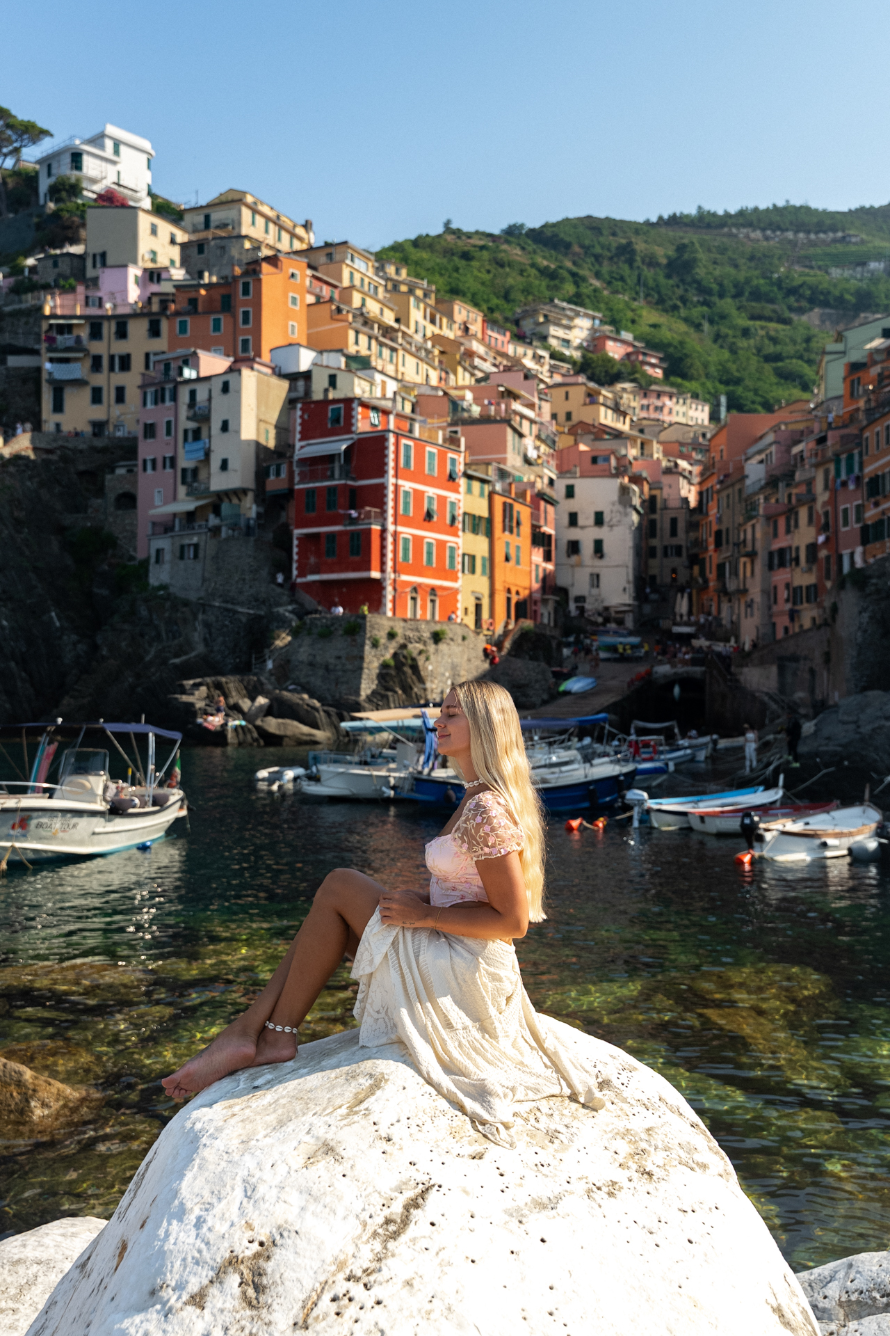 Woman sitting by Riomaggiore harbor in Cinque Terre, Italy