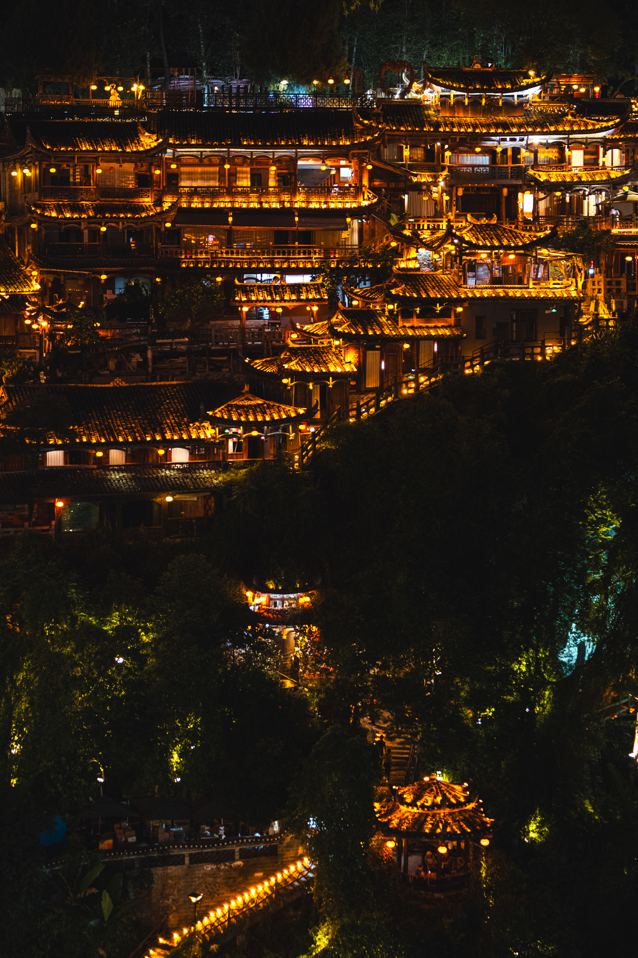 Traditional wooden buildings illuminated at night in Furong Ancient Town, Hunan, China.