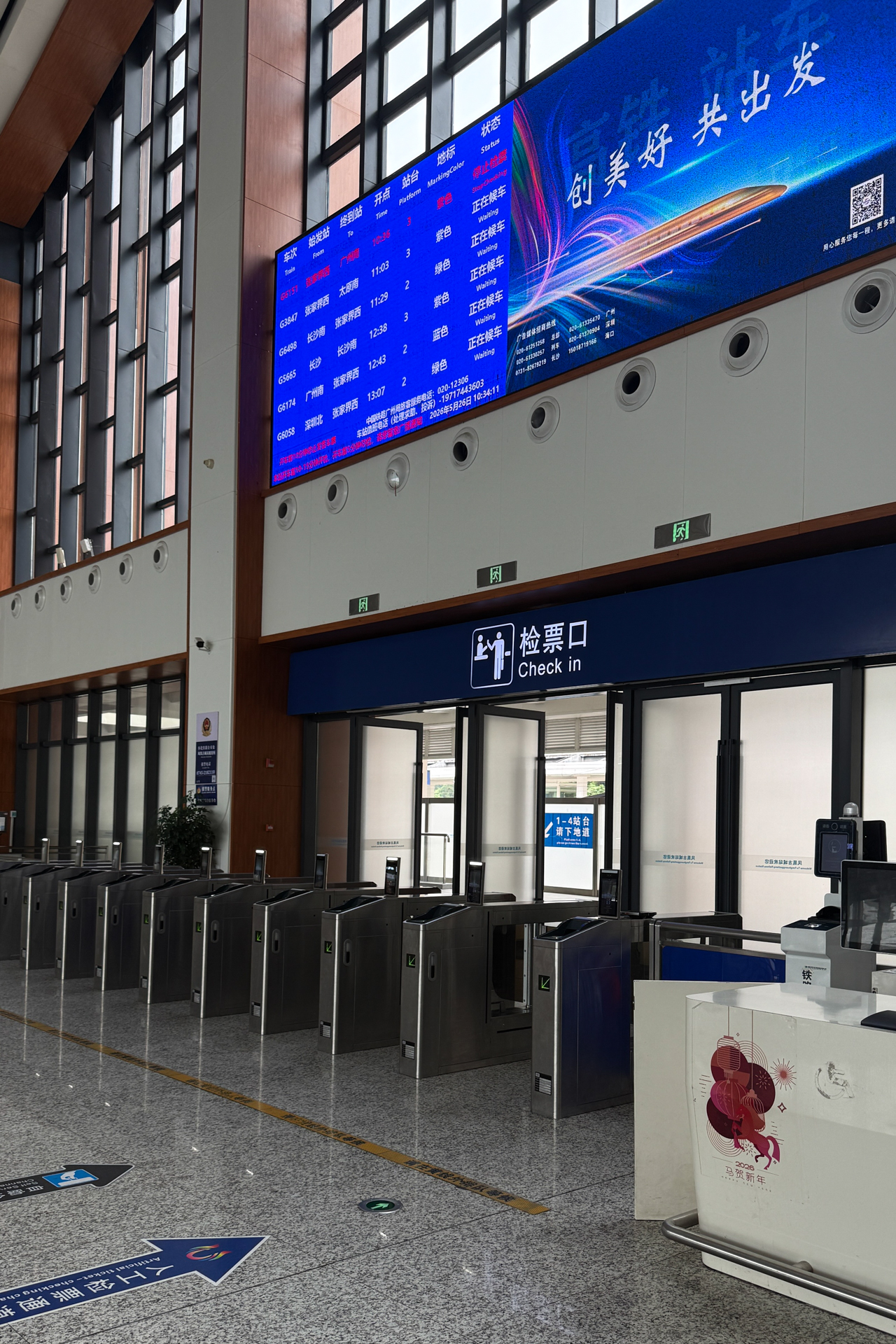 Check-in gates and departure board inside Furongzhen Railway Station in Hunan, China.