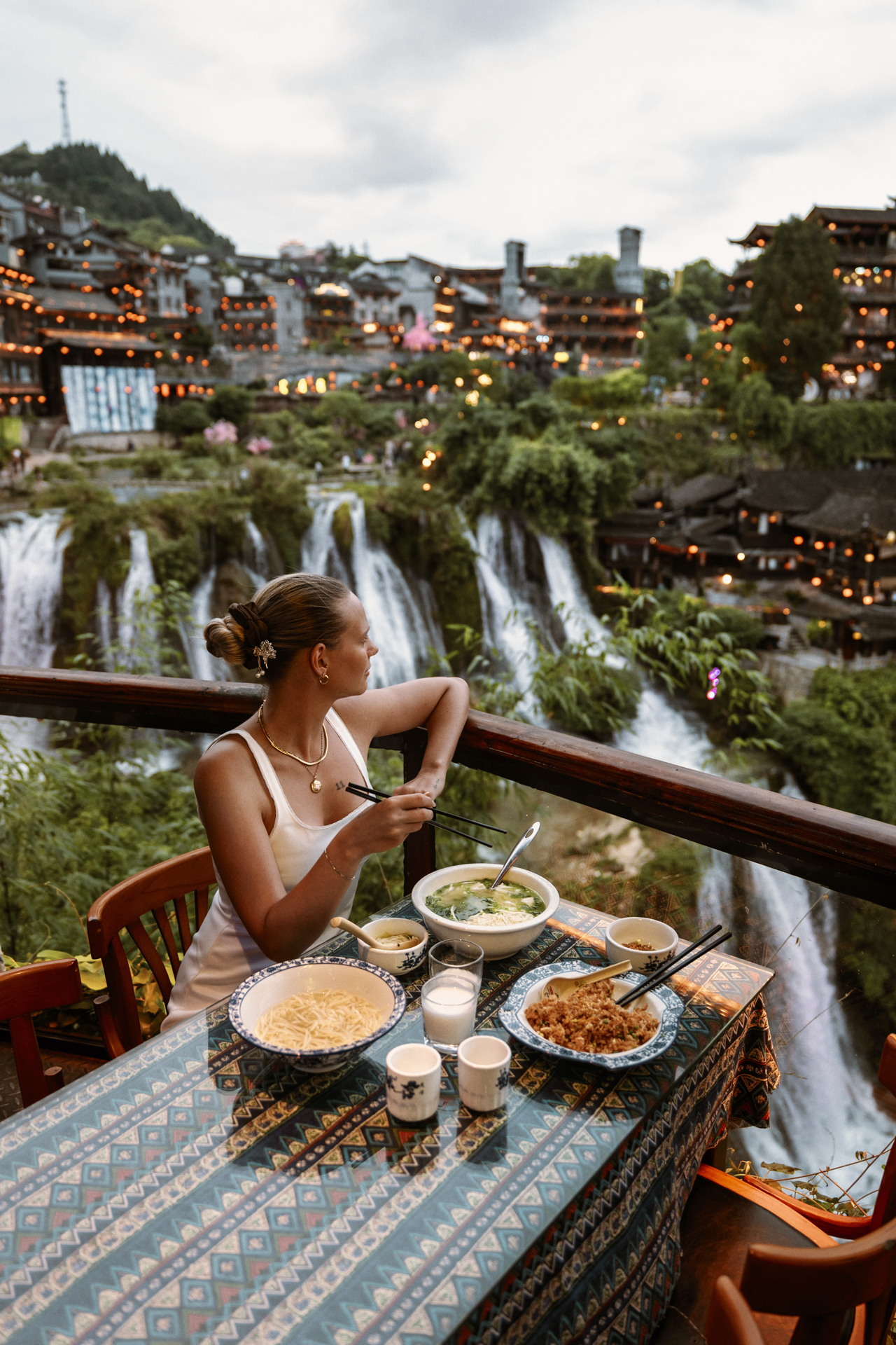 Restaurant overlooking Furong Ancient Town waterfalls and traditional buildings in China.