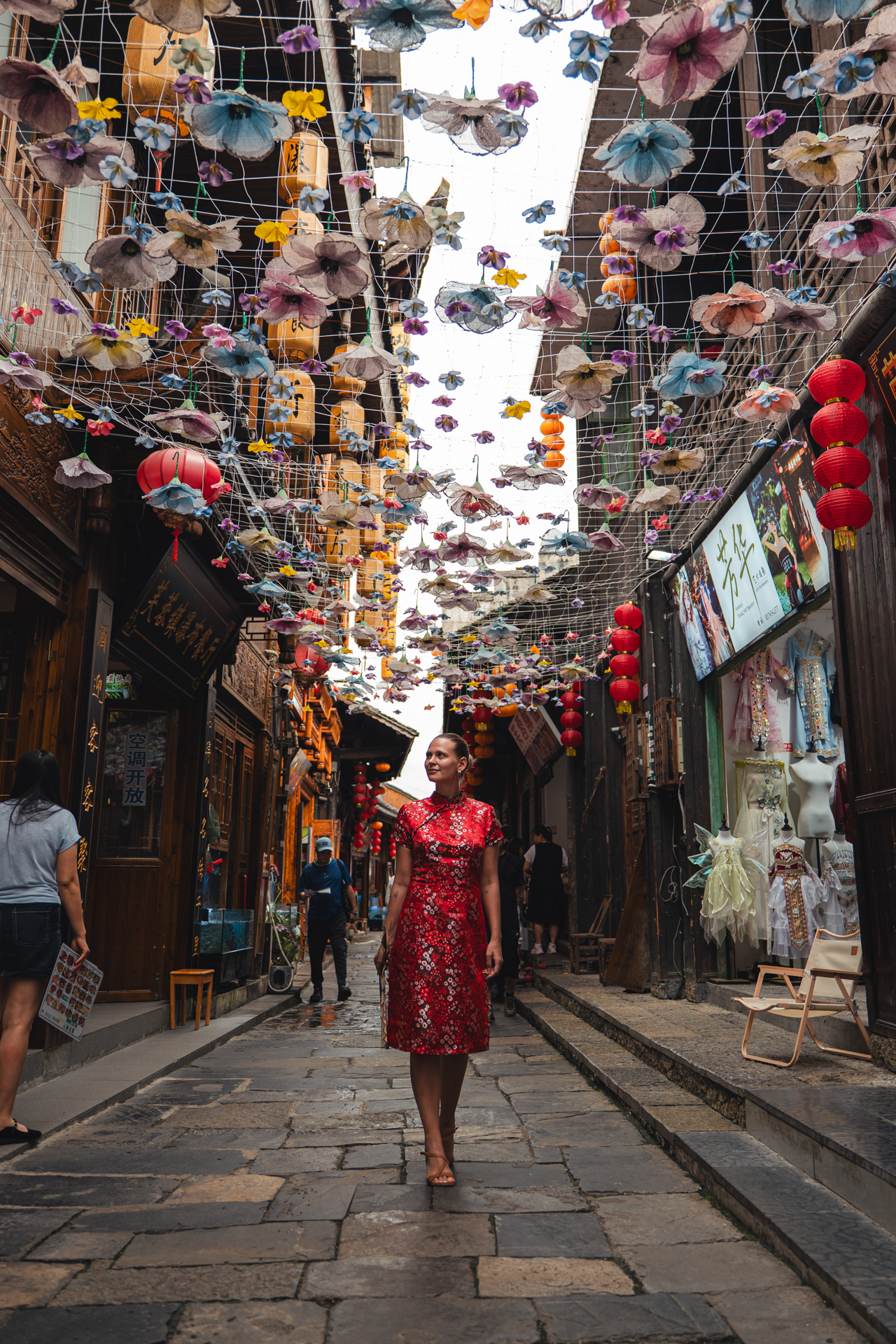 Woman in a red dress walking through a lantern-decorated street in Furong Ancient Town.