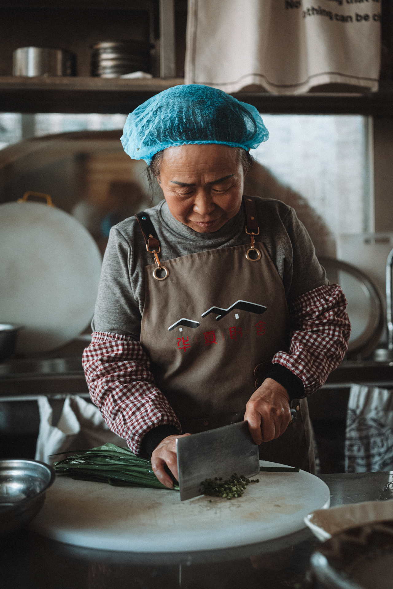 Local cook chopping fresh green onions in a traditional kitchen in Harbin, China.