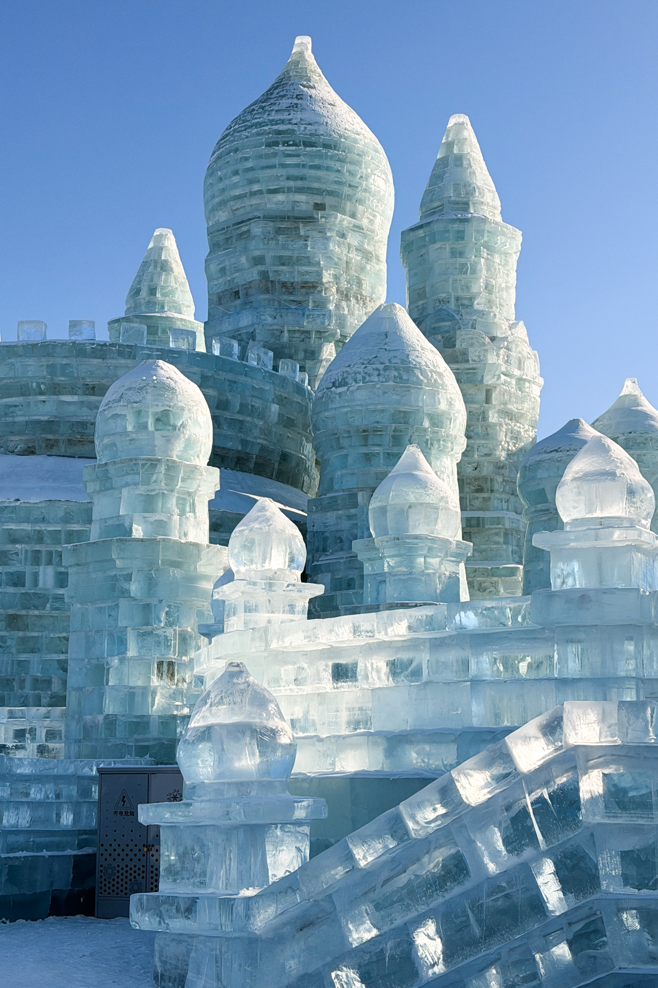 Detailed ice castle towers glowing in the winter sun at Harbin Ice and Snow World.