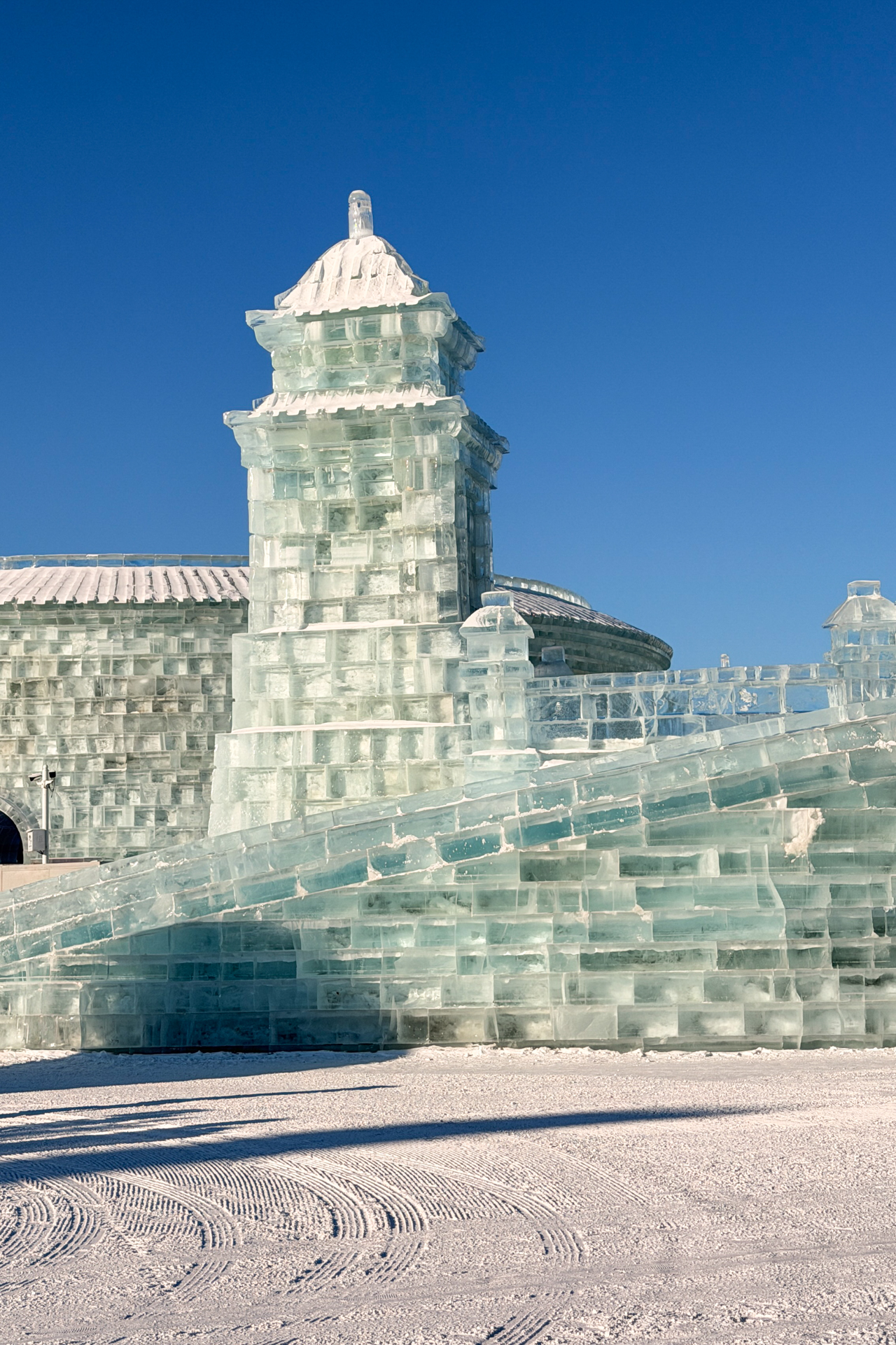 Detailed ice tower and bridge built from transparent blocks at Harbin Ice and Snow World.