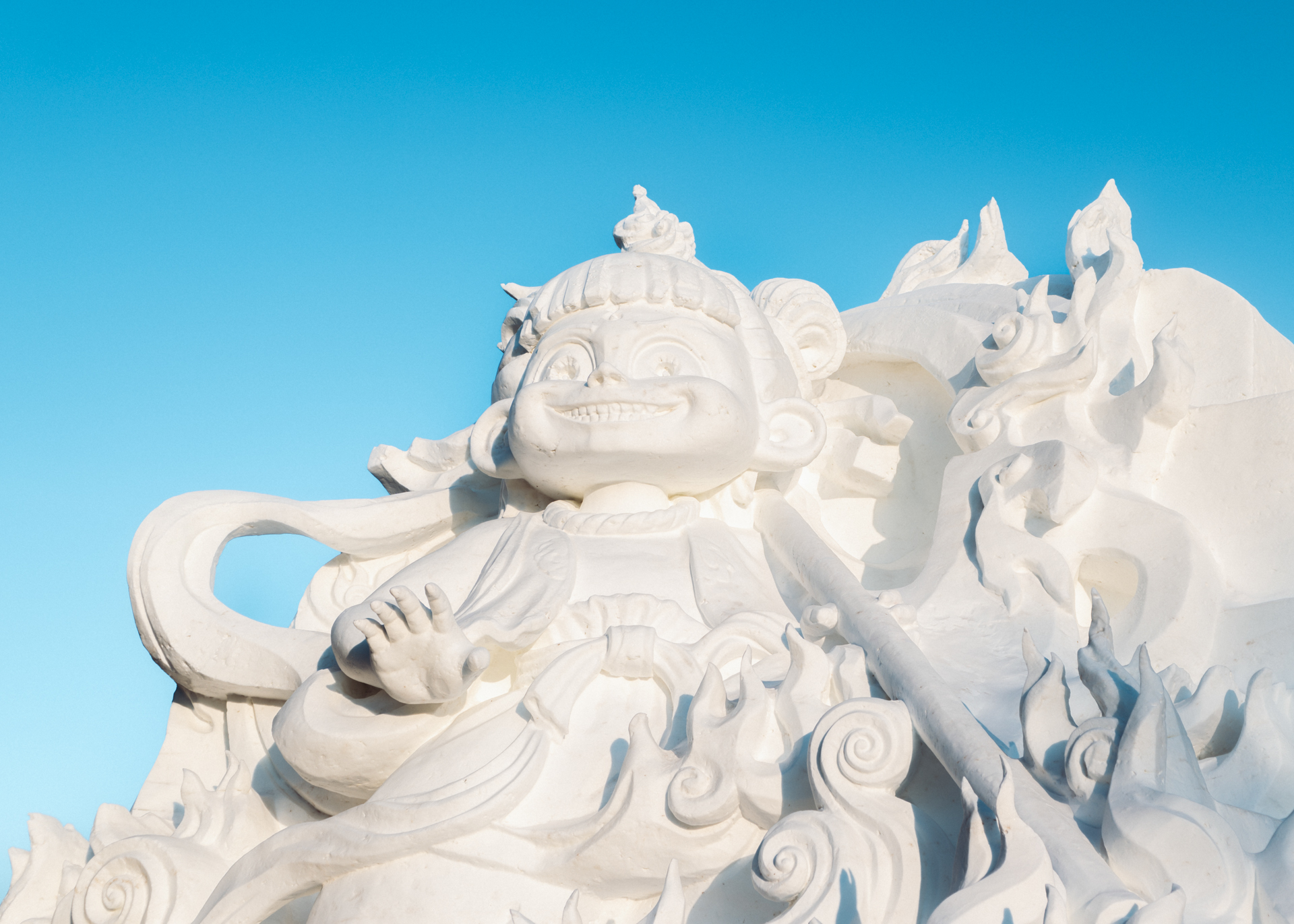 Snow sculpture of a mythical monkey figure at Harbin’s winter festival under a clear blue sky.