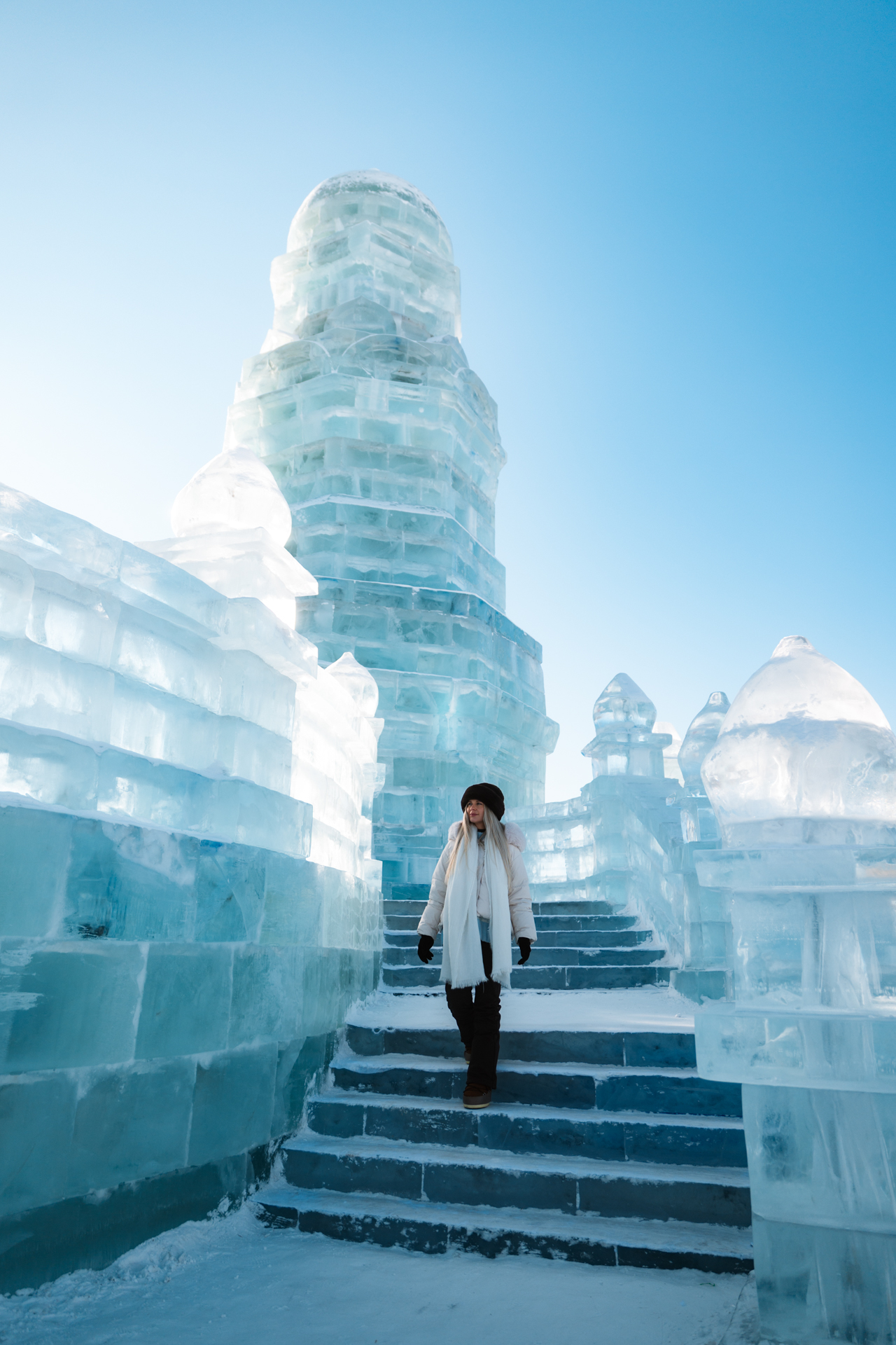 Woman walking through towering ice structures at Harbin Ice and Snow World in China.