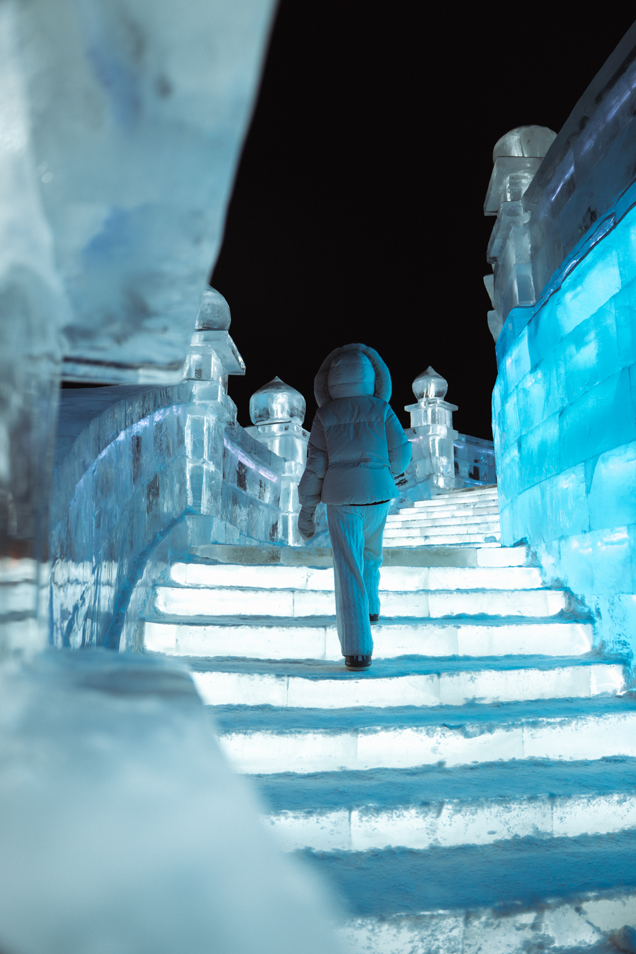Walking up glowing ice stairs at Harbin Ice and Snow World at night.