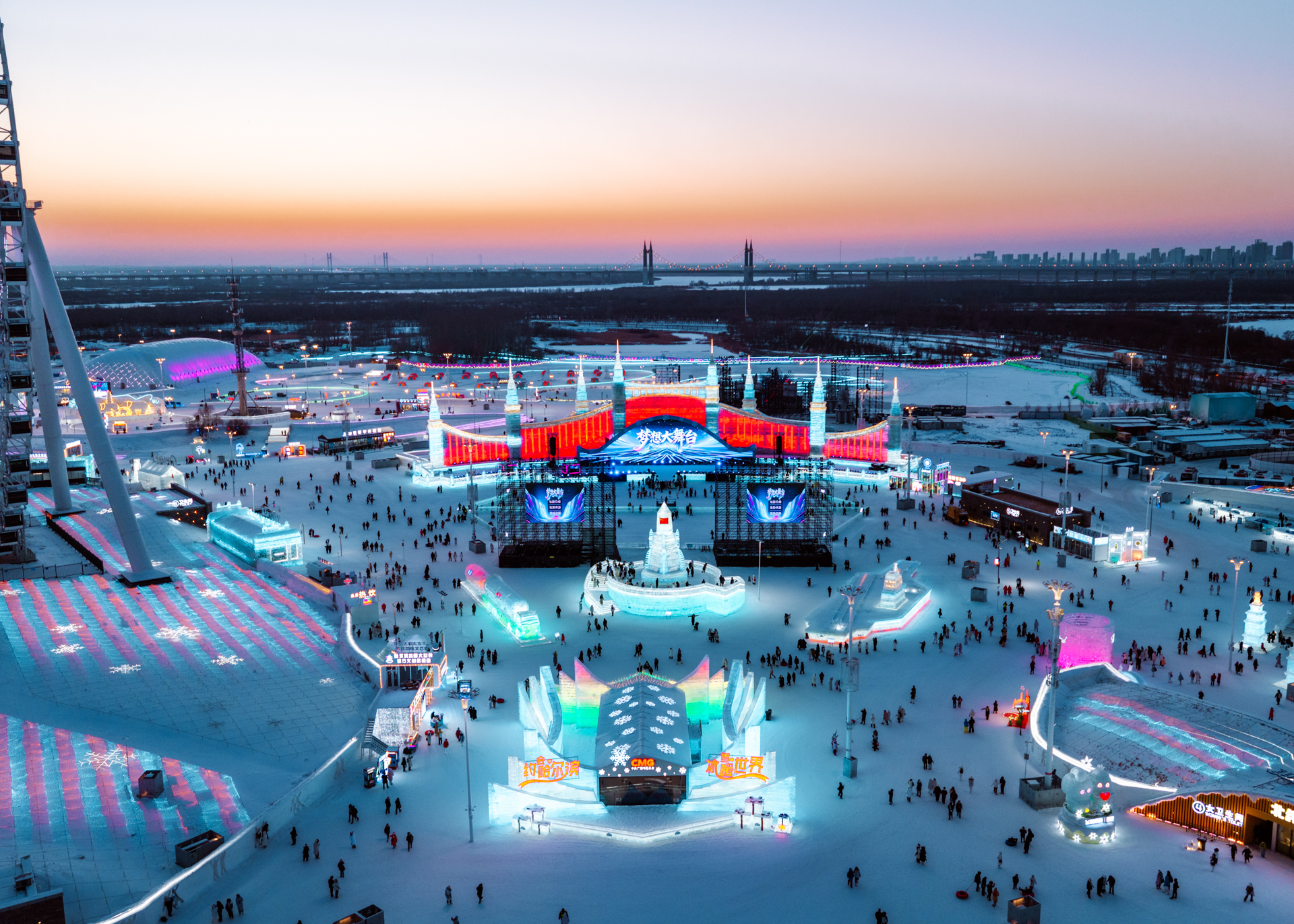 Harbin Ice and Snow World illuminated at sunset with colorful ice sculptures and festival grounds.