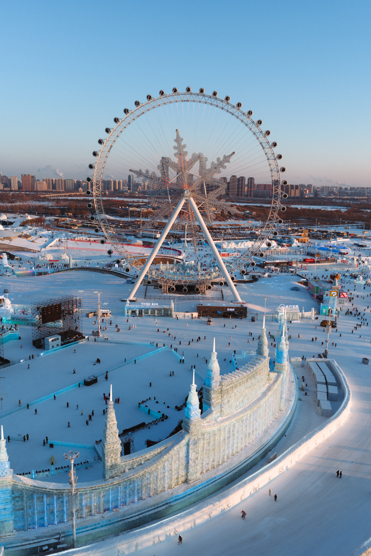 Aerial view of Harbin Ice and Snow World with a giant Ferris wheel and ice sculptures, China.