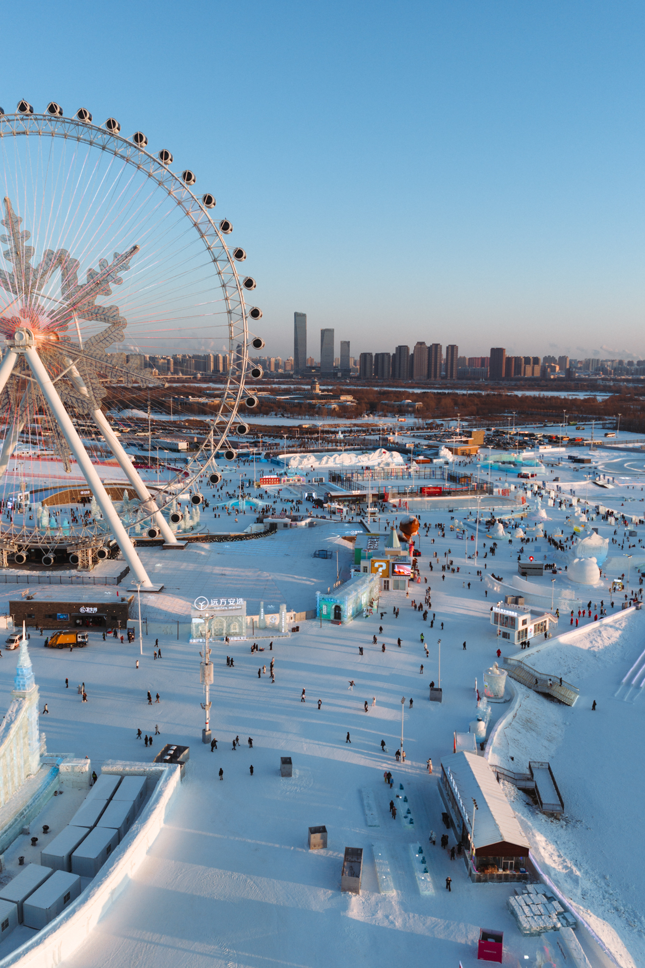 Aerial view of Harbin Ice and Snow World with its giant Ferris wheel and snowy festival grounds.