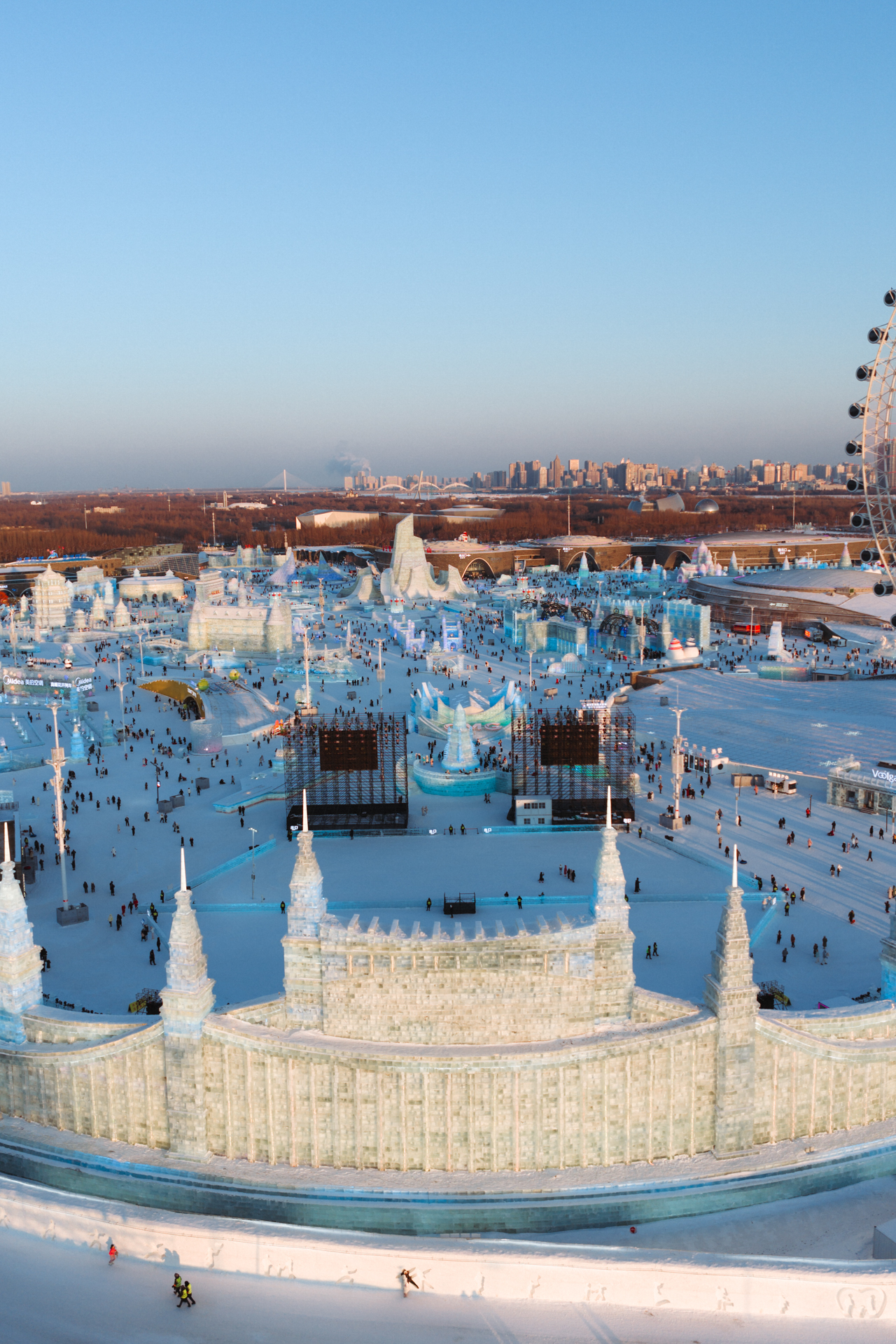Aerial view of Harbin Ice and Snow World with massive ice structures and the city skyline.
