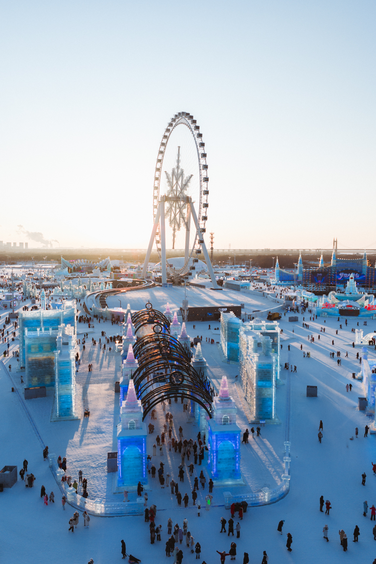 Ferris wheel overlooking ice sculptures and visitors at Harbin Ice and Snow World.