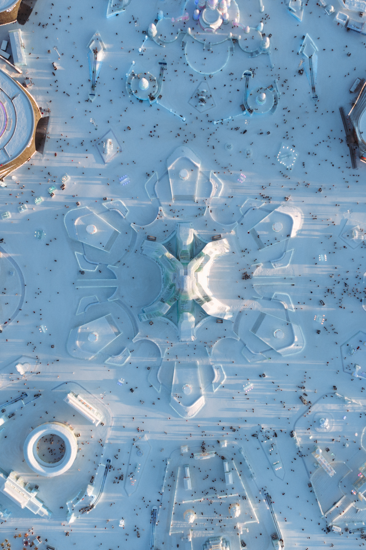 Aerial view of Harbin Ice and Snow World with symmetrical ice structures and visitors.