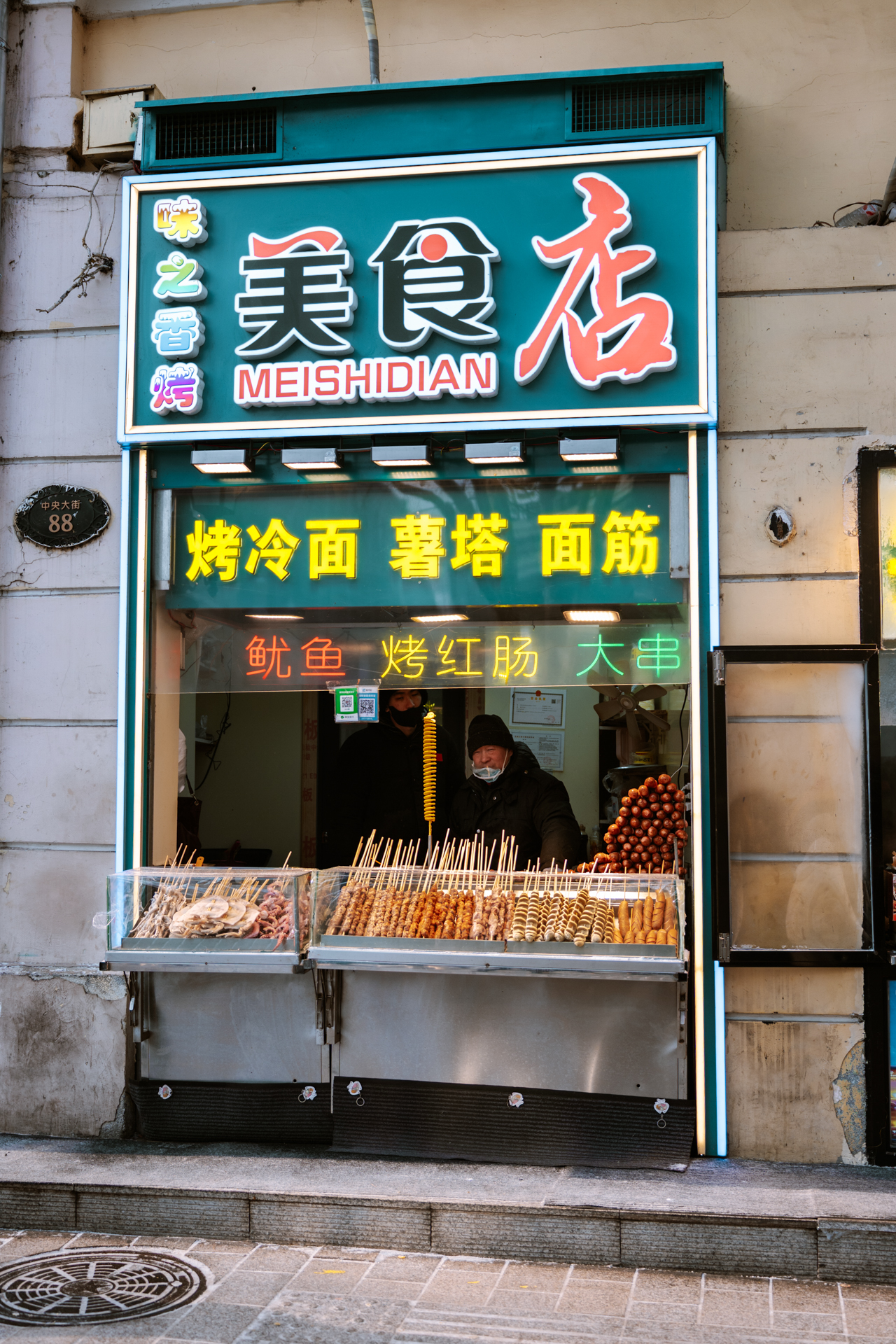 Street food stall selling grilled skewers and snacks on Central Street in Harbin, China.