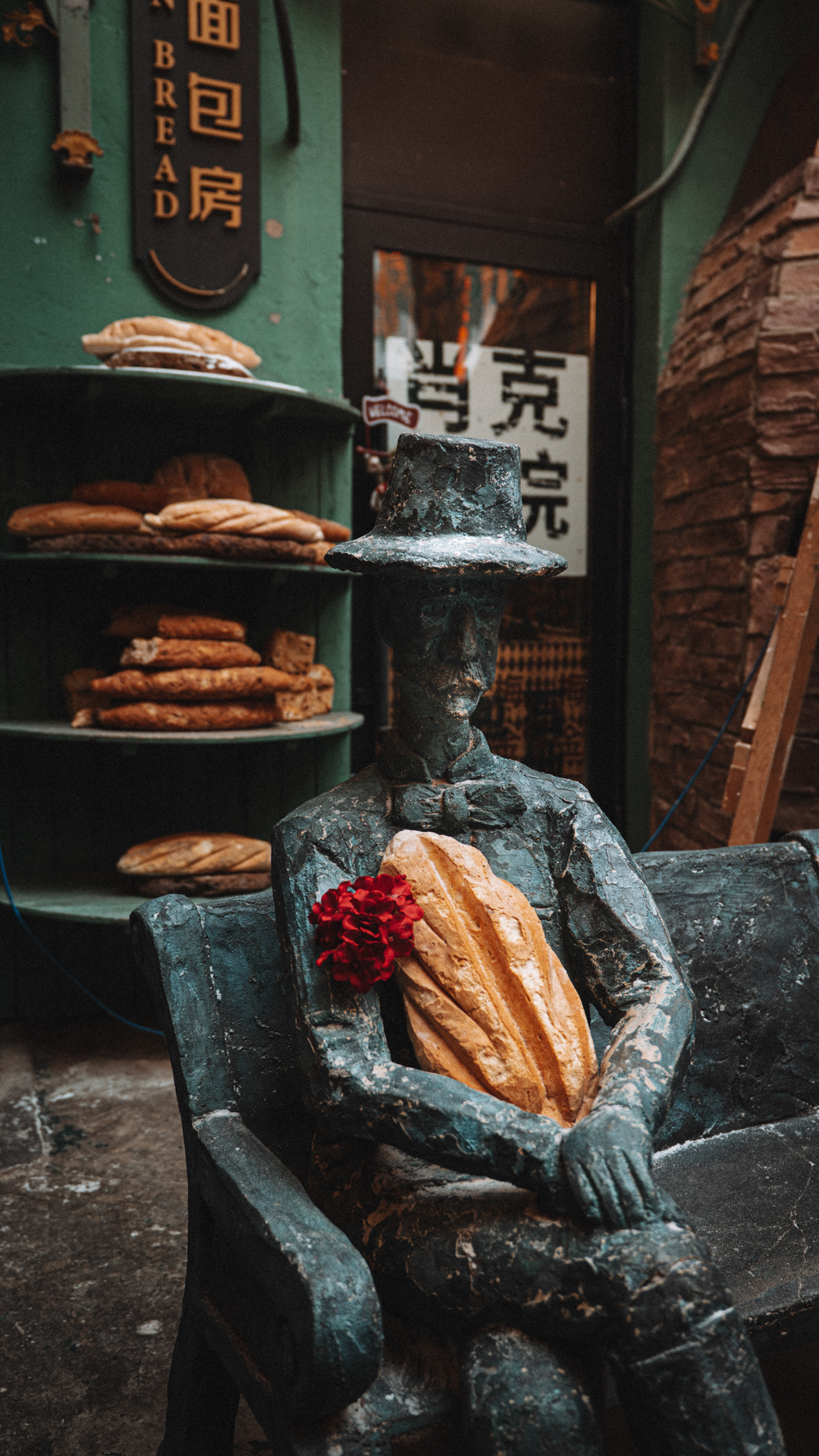 Bronze figure holding a loaf of bread outside a bakery in Harbin, China.