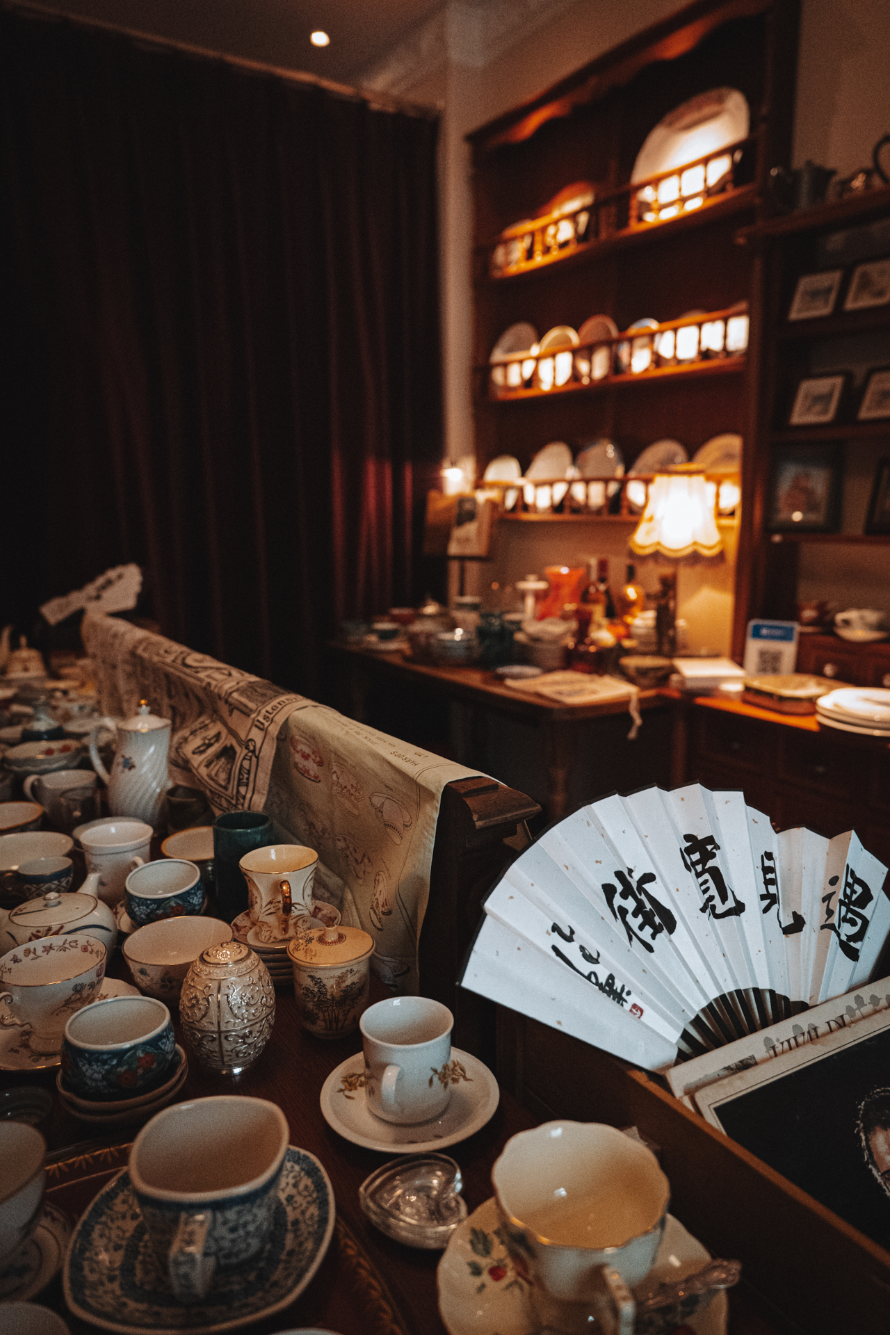 Traditional teacups and a Chinese calligraphy fan displayed inside a cozy Harbin shop.