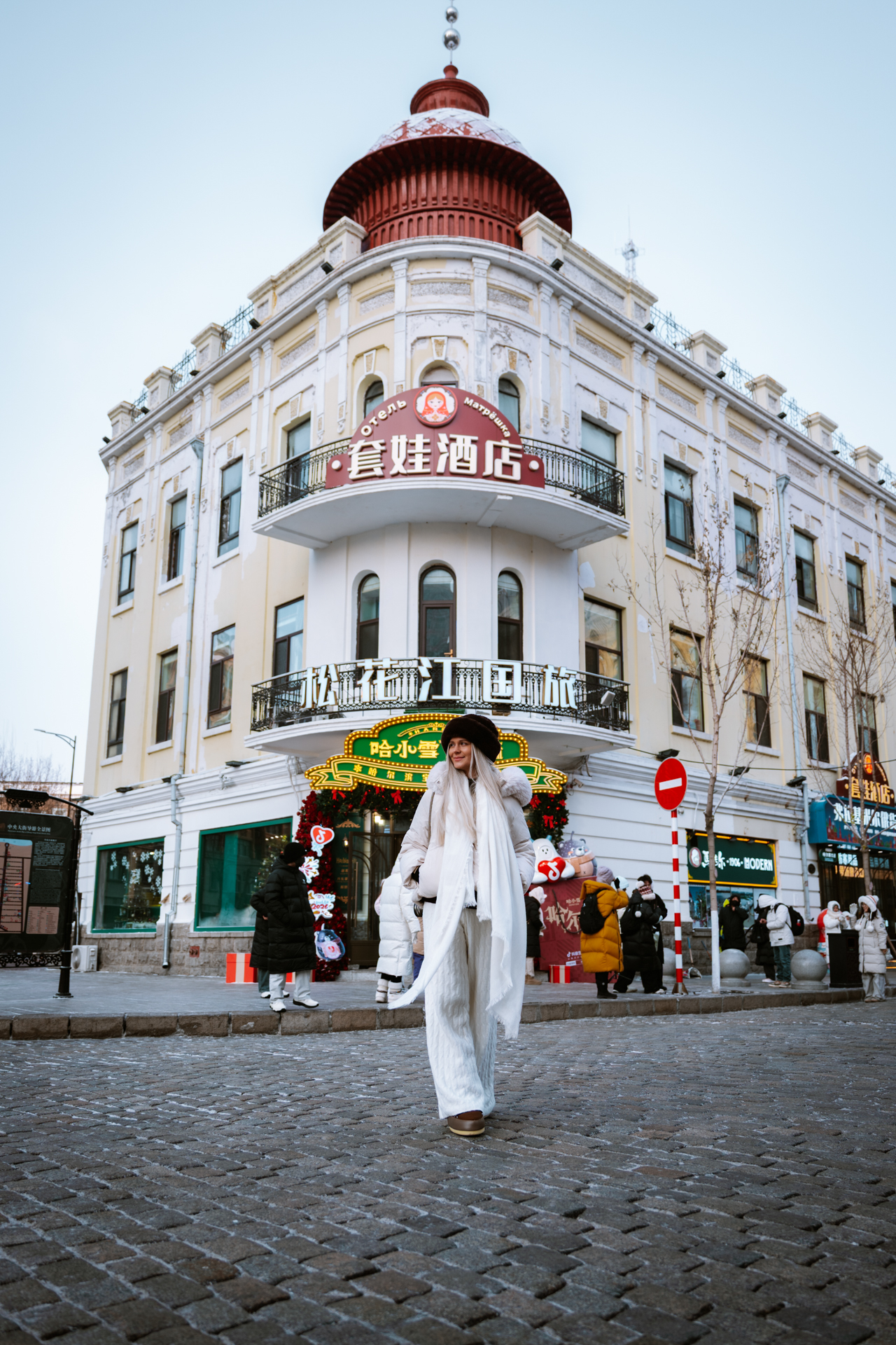 Woman walking along Zhongyang Street in winter, surrounded by historic architecture in Harbin, China.