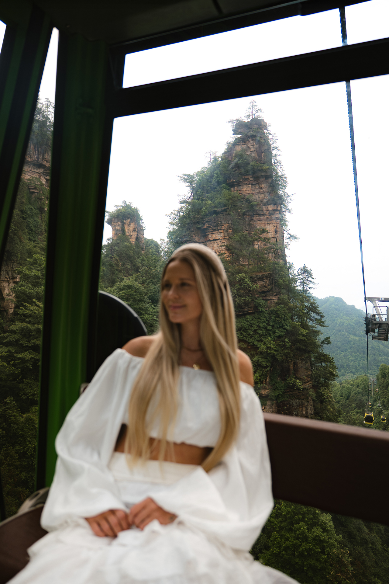 Woman riding a cable car through the sandstone peaks of Zhangjiajie National Forest Park.