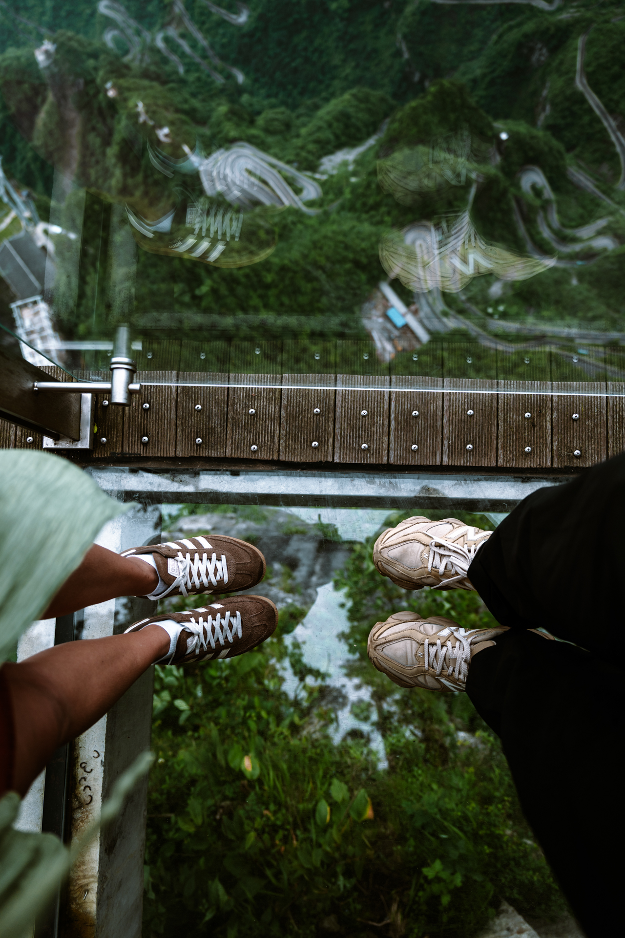 Glass skywalk overlooking the winding mountain road at Tianmen Mountain, Zhangjiajie.