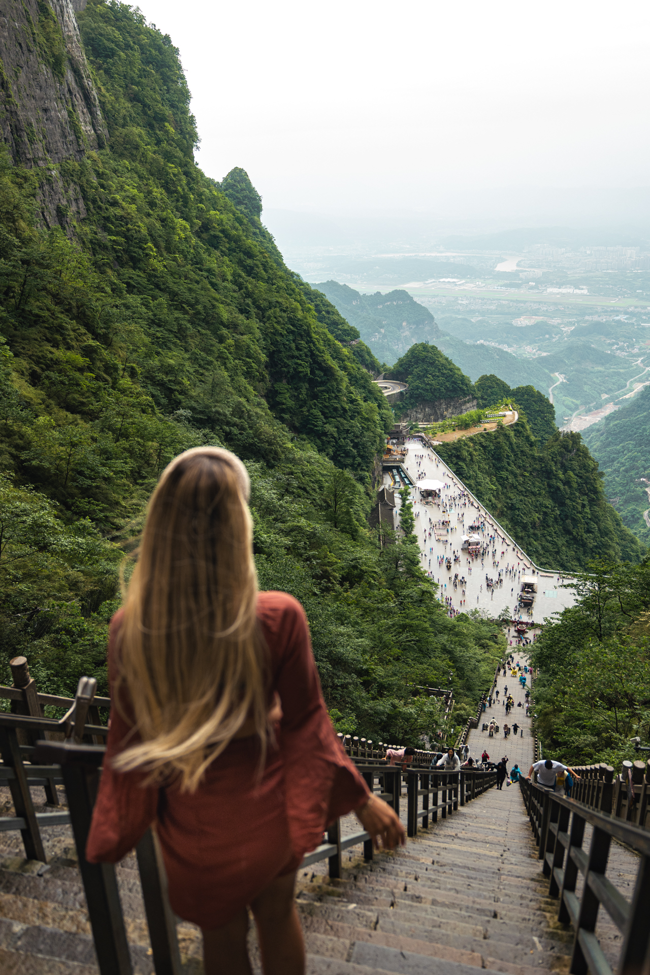 Woman descending the 999 Steps at Tianmen Mountain with views over Zhangjiajie, China.
