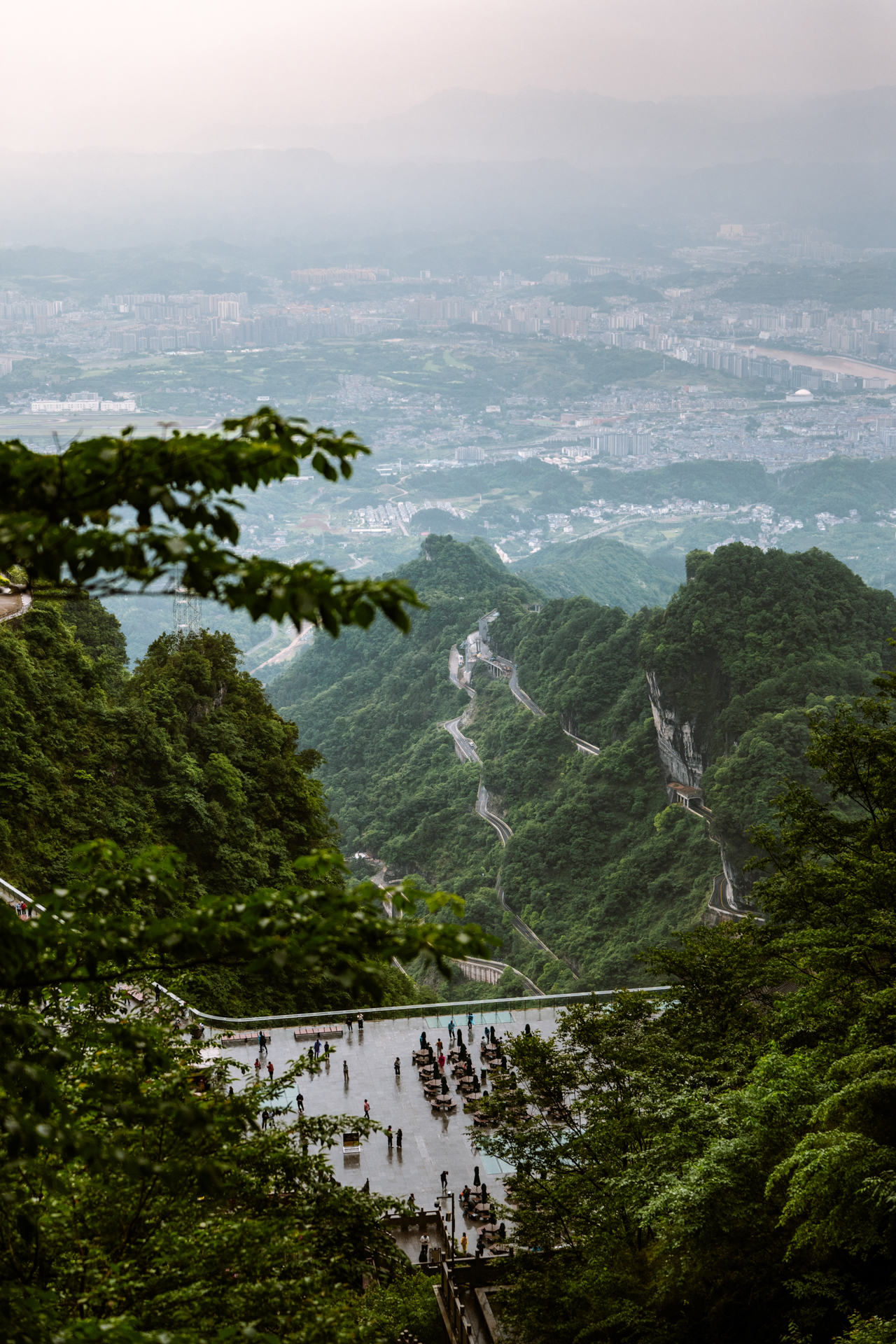 View over Zhangjiajie from Tianmen Mountain with winding mountain roads below.