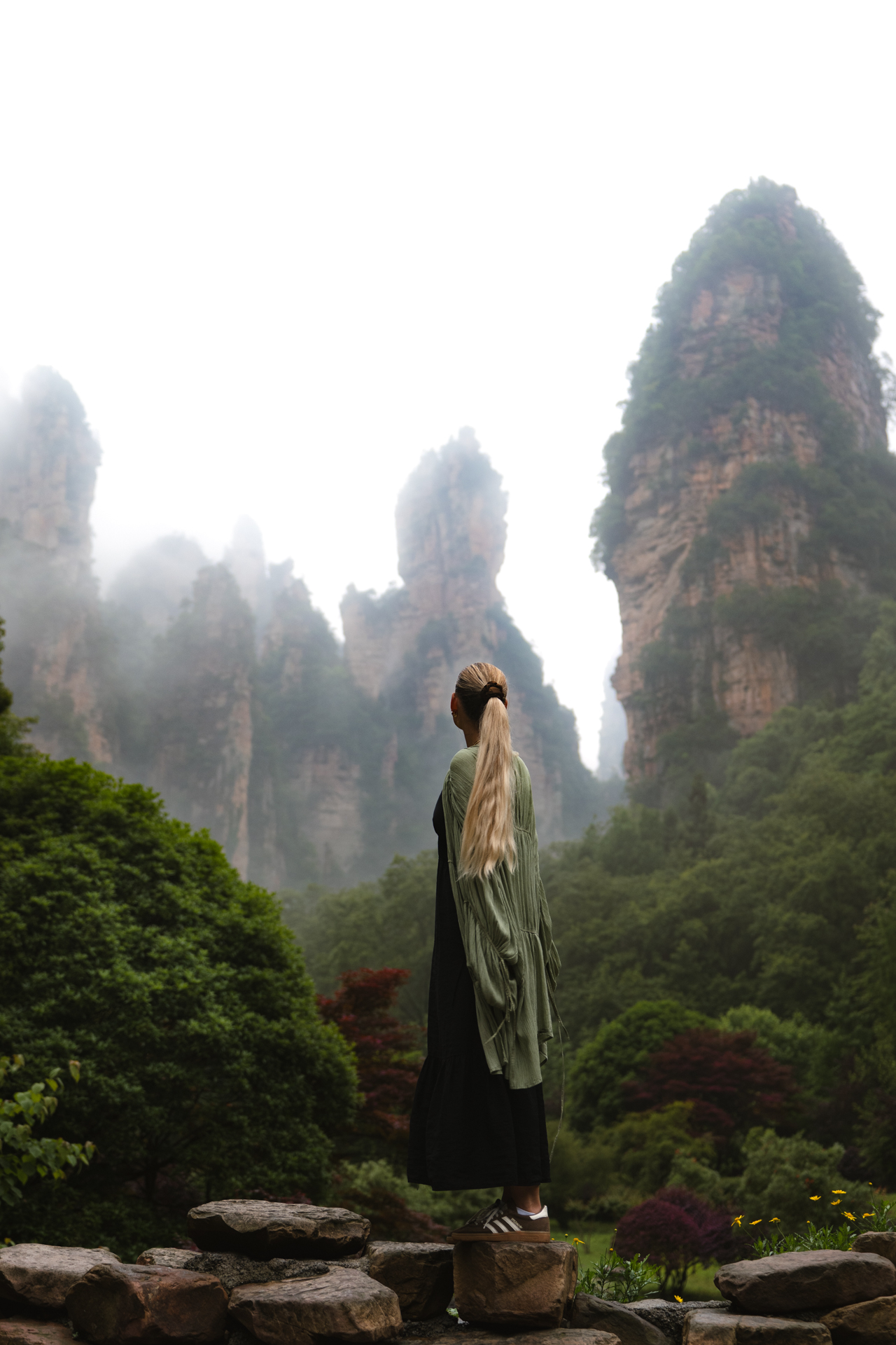 Woman overlooking the misty sandstone pillars of Zhangjiajie National Forest Park, China.
