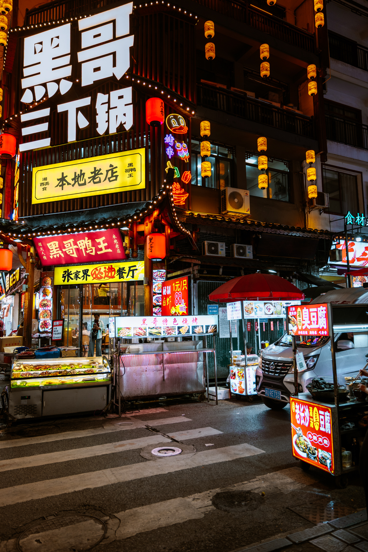 Night street food stalls and local restaurants glowing with neon signs in Zhangjiajie, China