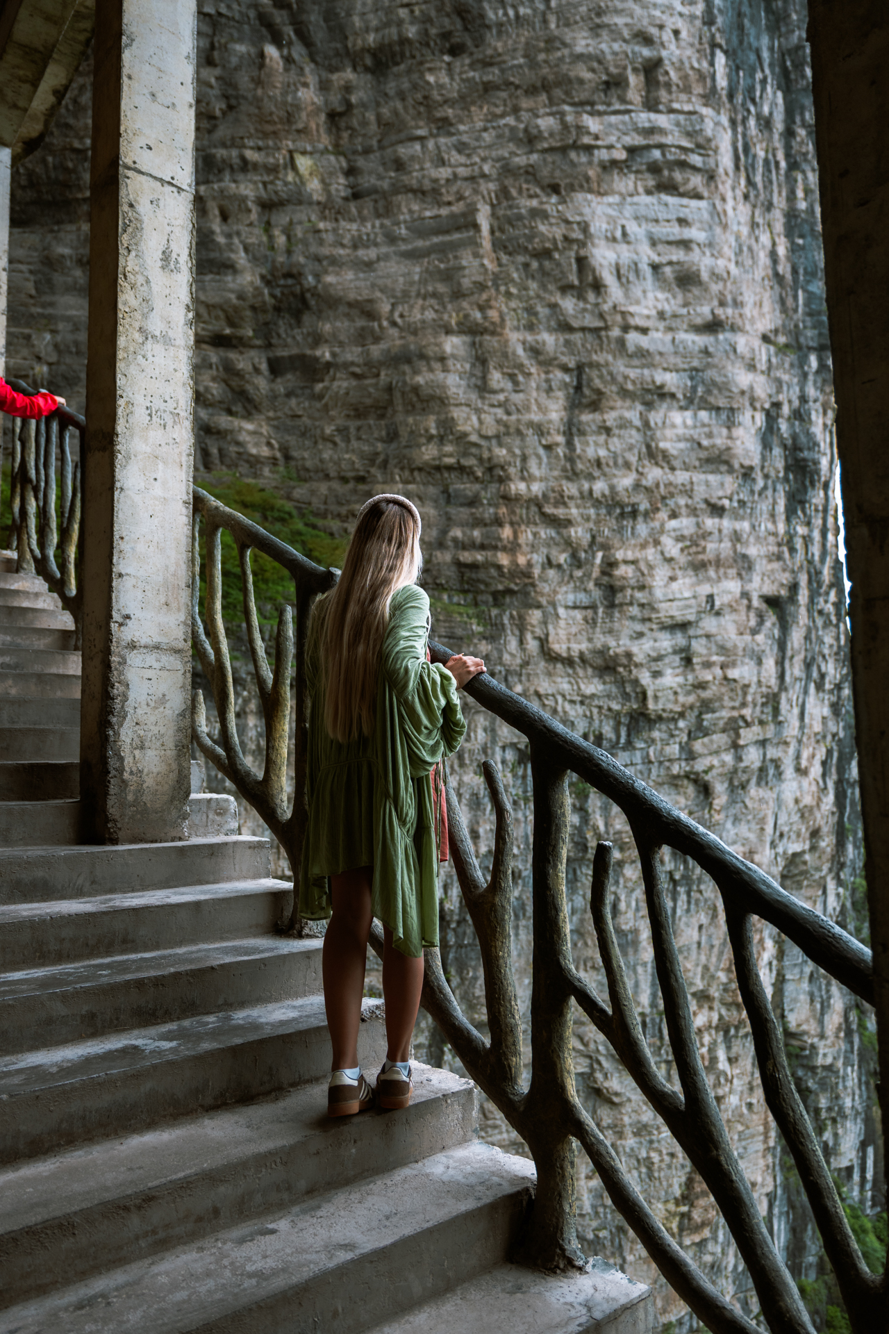 Woman overlooking a dramatic cliff from a stairway in Zhangjiajie National Forest Park, China.